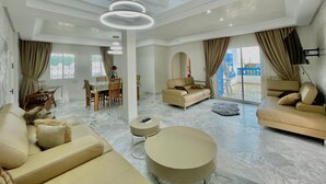 A spacious living room with a sofa, a round coffee table, and a dining area with a table and chairs. - BLUE SKY SIDI BOUSAID (Carthage)