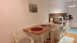 Eine kleine Küche mit Holztisch, Mikrowelle und Kühlschrank.