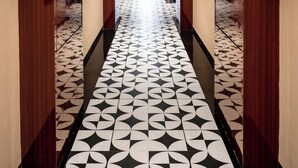 Un pasillo con suelo de diseño geométrico, paredes espejadas y paneles de madera.