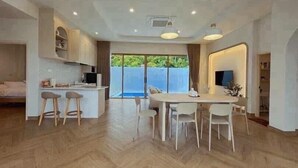 A spacious kitchen with a dining area, large windows, and a view of greenery. - Level TWO pool villa Sriracha (Si Racha)