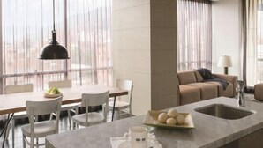 A modern kitchen with a marble countertop, a dining area with white chairs, and a sofa in the background. - w Bright 1BR w View in El Nogal (Bogotá)