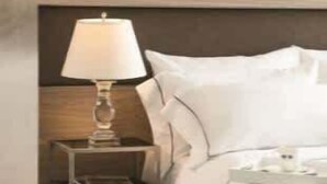 Een hotelkamer met een bed, een nachtkastje met lamp en een kamerkleed met dessin.
