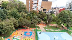 A playground with colorful play areas and basketball courts surrounded by trees and buildings.