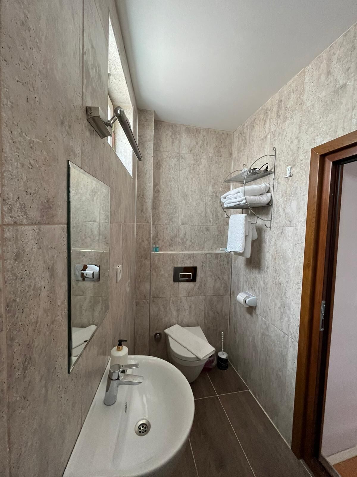 A bathroom with a sink, mirror, towel rack, and toilet.