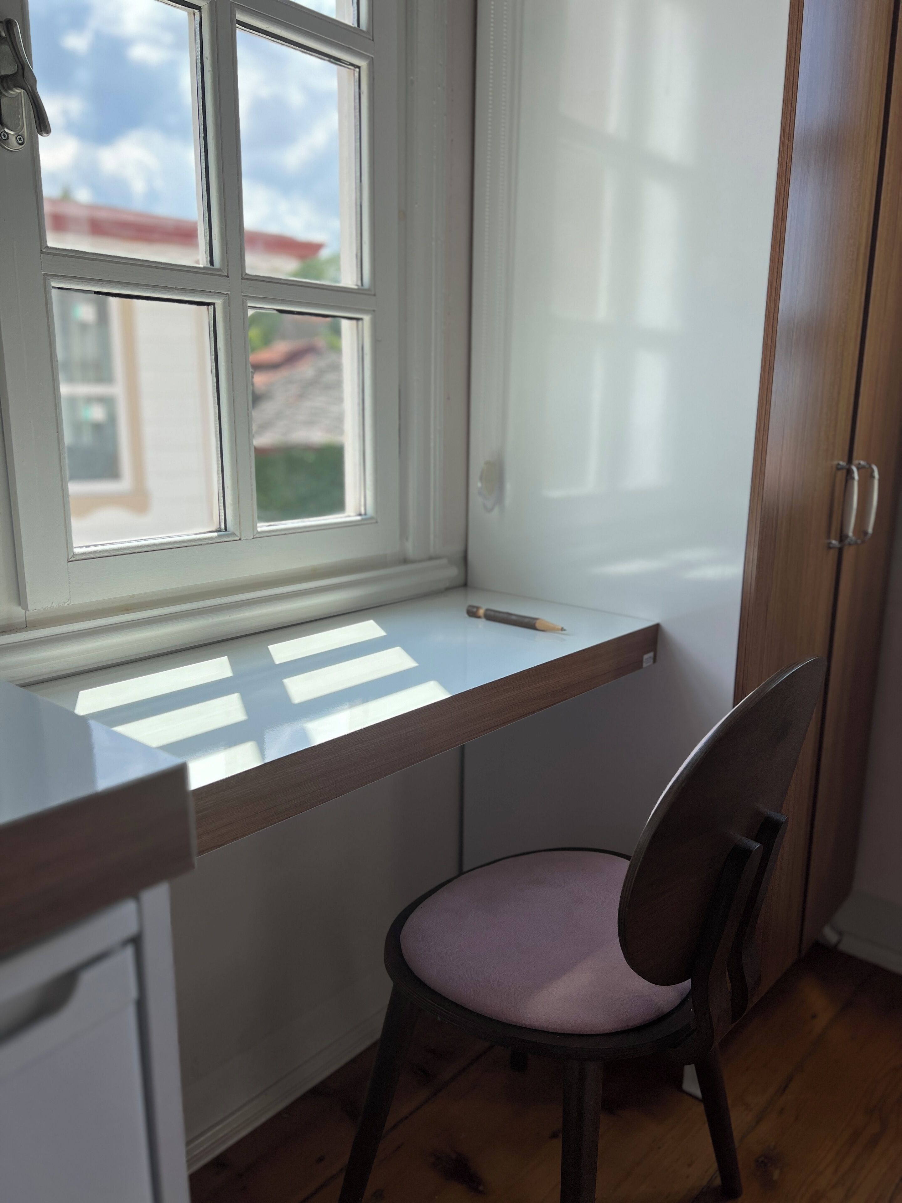 Un piccolo angolo studio con finestra, una sedia e un armadietto in legno.