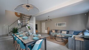 A modern living room with a sofa, coffee table, and dining area with chairs and a table set for a meal.