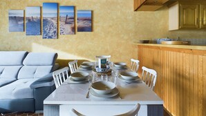 A dining area with a table set for six, white chairs, and a wooden ceiling.