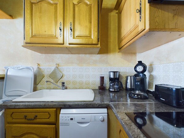 A kitchen with wooden cabinets, a dishwasher, a coffee maker, and a toaster. - Sea view - apartment for 6 on St Gilles (Saint-Gilles-Croix-de-Vie)