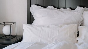 Una cama bien hecha con sábanas blancas y un cabecero oscuro.