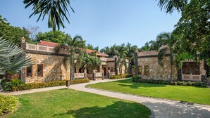 A courtyard with stone buildings, palm trees, and a paved walkway. - Vikrama Heritage Resort Pavagadh (Halol)