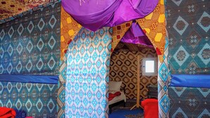 A room with patterned walls and a bed with a red pillow.