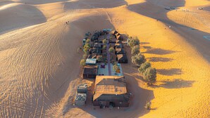 An aerial view of a desert resort with multiple tents and caravans arranged in a linear formation.