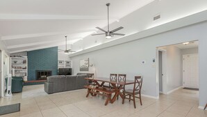 Un vaste espace de vie comprenant une table à manger, des chaises, une cheminée et un ventilateur de plafond.