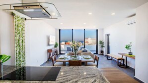 A modern kitchen with a granite countertop, a built-in stove, and a large window overlooking a cityscape. - Torre Doze Private Penthouse (Puerto Vallarta)