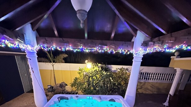Un bain à remous installé dans un espace abrité et illuminé de guirlandes lumineuses.