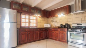 Une cuisine équipée de meubles en bois, d’un réfrigérateur, d’un four à micro-ondes, d’une machine à café et d’un four.