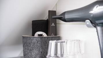 Un coin de pièce avec une boîte noire portant l’inscription « ALGOTHERM », un récipient gris texturé contenant un objet noir, et une bouteille en verre transparent.