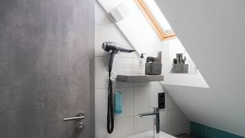 Une salle de bain moderne dotée d’une lucarne, d’un sèche-cheveux, d’un lavabo et d’étagères de rangement.