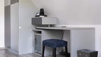 Habitació moderna i minimalista amb escriptori integrat, una cadira, un petit armari i un gresol.