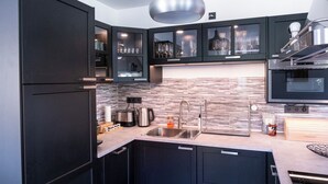 A modern kitchen with dark cabinets, a stainless steel sink, and a tiled backsplash.