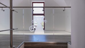 A modern interior with a glass railing, a wooden floor, and a cat-shaped cutout on the wall.
