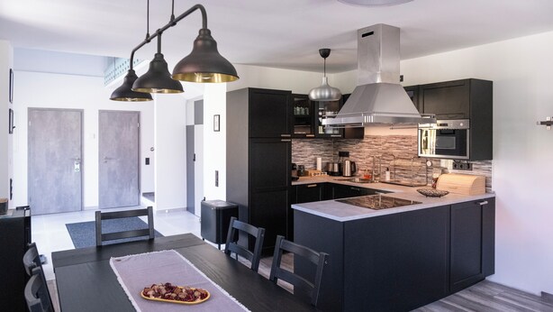 A modern kitchen with dark cabinetry, a central island, and pendant lighting.