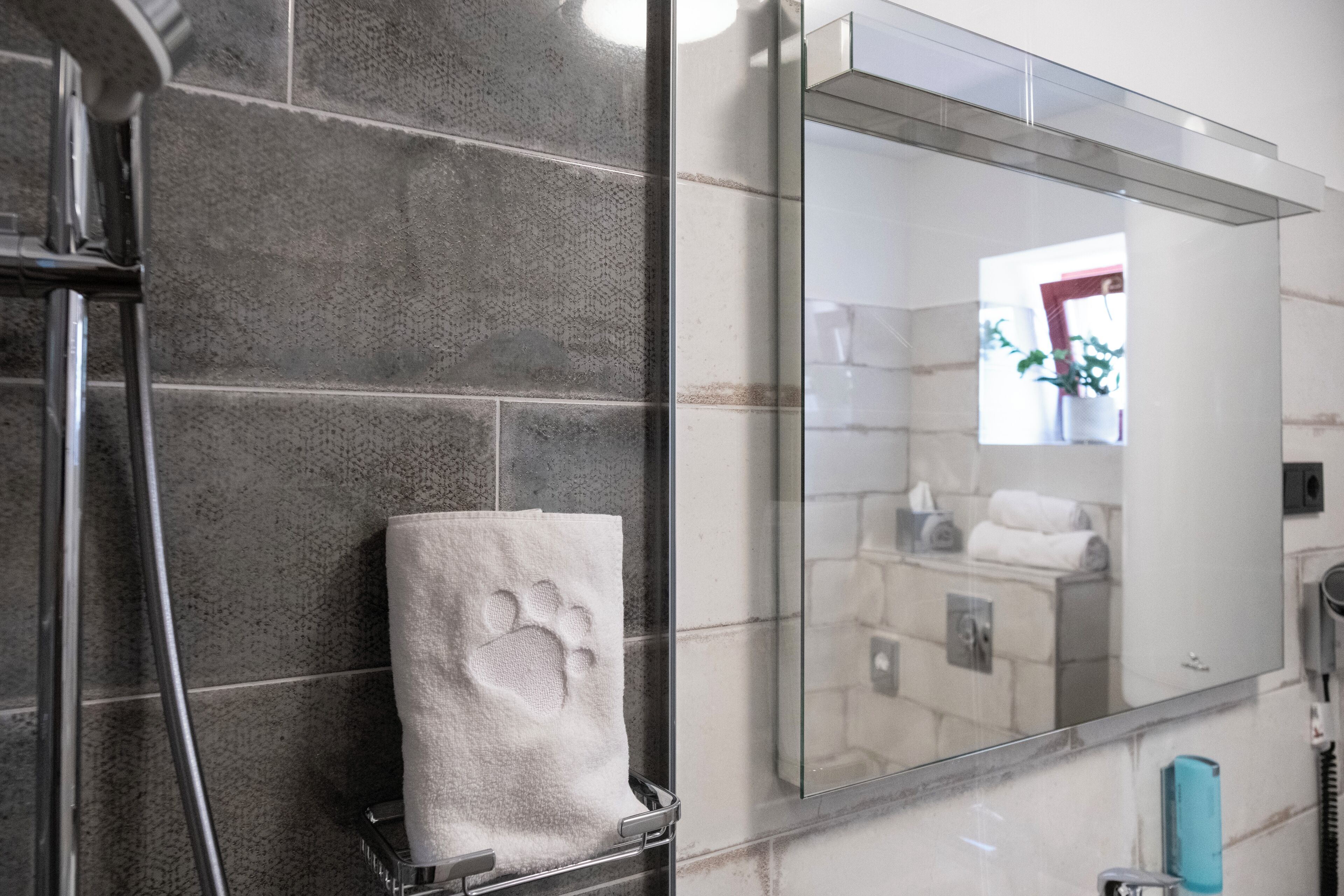 Un baño con un espejo grande, un perchero con una toalla y una zona de ducha.