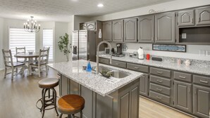 A modern kitchen with granite countertops, stainless steel appliances, and a breakfast bar with stools. - Private Deck & Game Room: Portland Group Getaway (Portland)