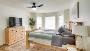 A bedroom with a bed, a TV on a wooden dresser, a ceiling fan, and a window with blinds. - Private Deck & Game Room: Portland Group Getaway (Portland)