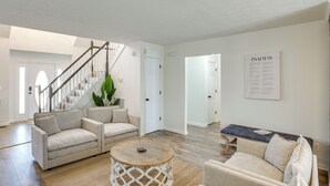 A spacious living room with a staircase, two sofas, a coffee table, and a wall-mounted Bible. - Private Deck & Game Room: Portland Group Getaway (Portland)