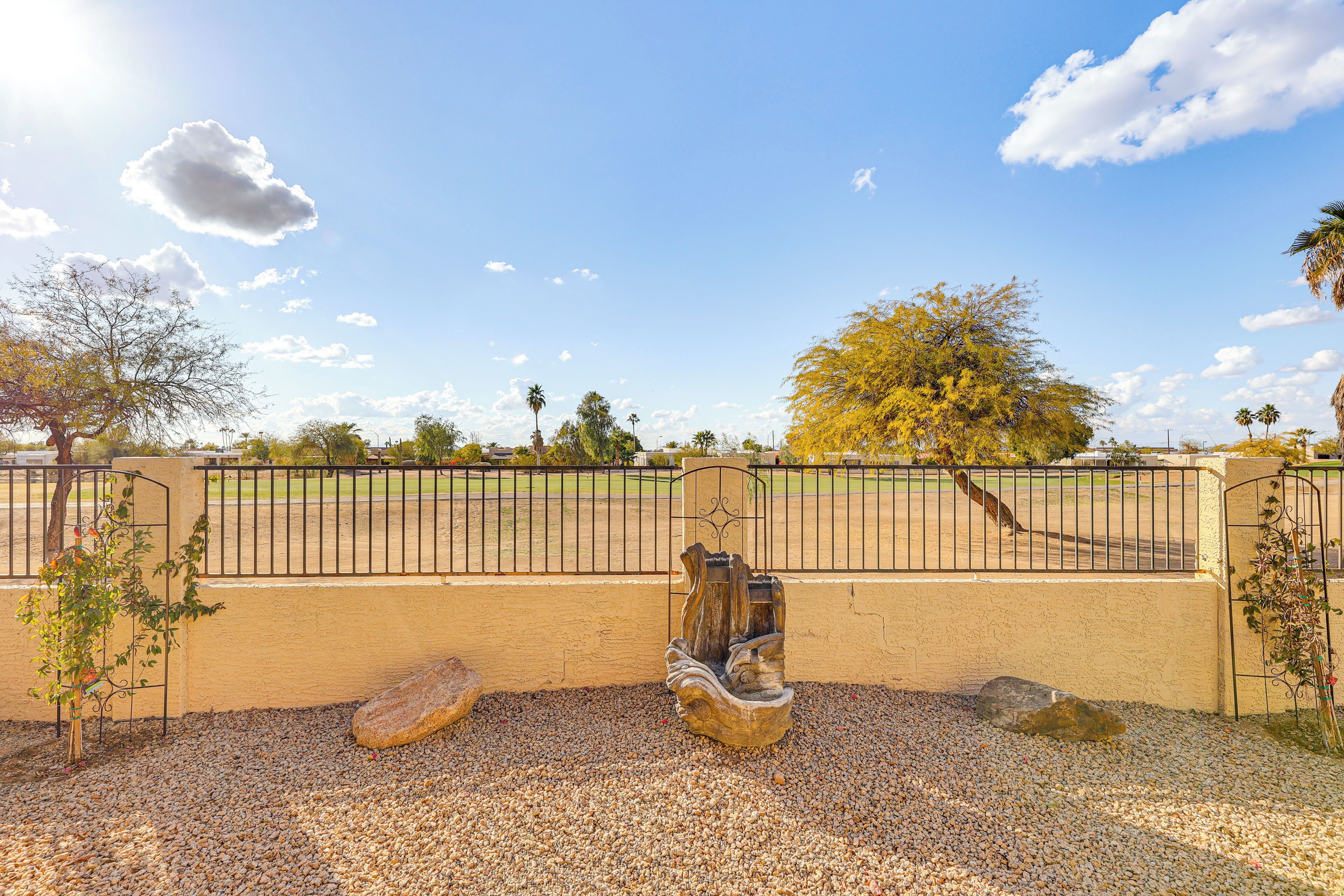 Un parc doté d’un chemin pavé, d  ’une clôture en métal et d’une sculpture.