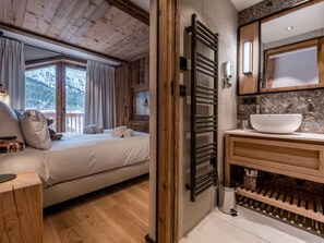 Experience a warm and inviting atmosphere in this stylish room, featuring a large bed, wooden nightstand, and scenic mountain views.