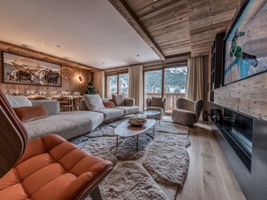 Relax in this inviting living space with a plush sectional sofa, armchairs, and a large flat-screen TV.