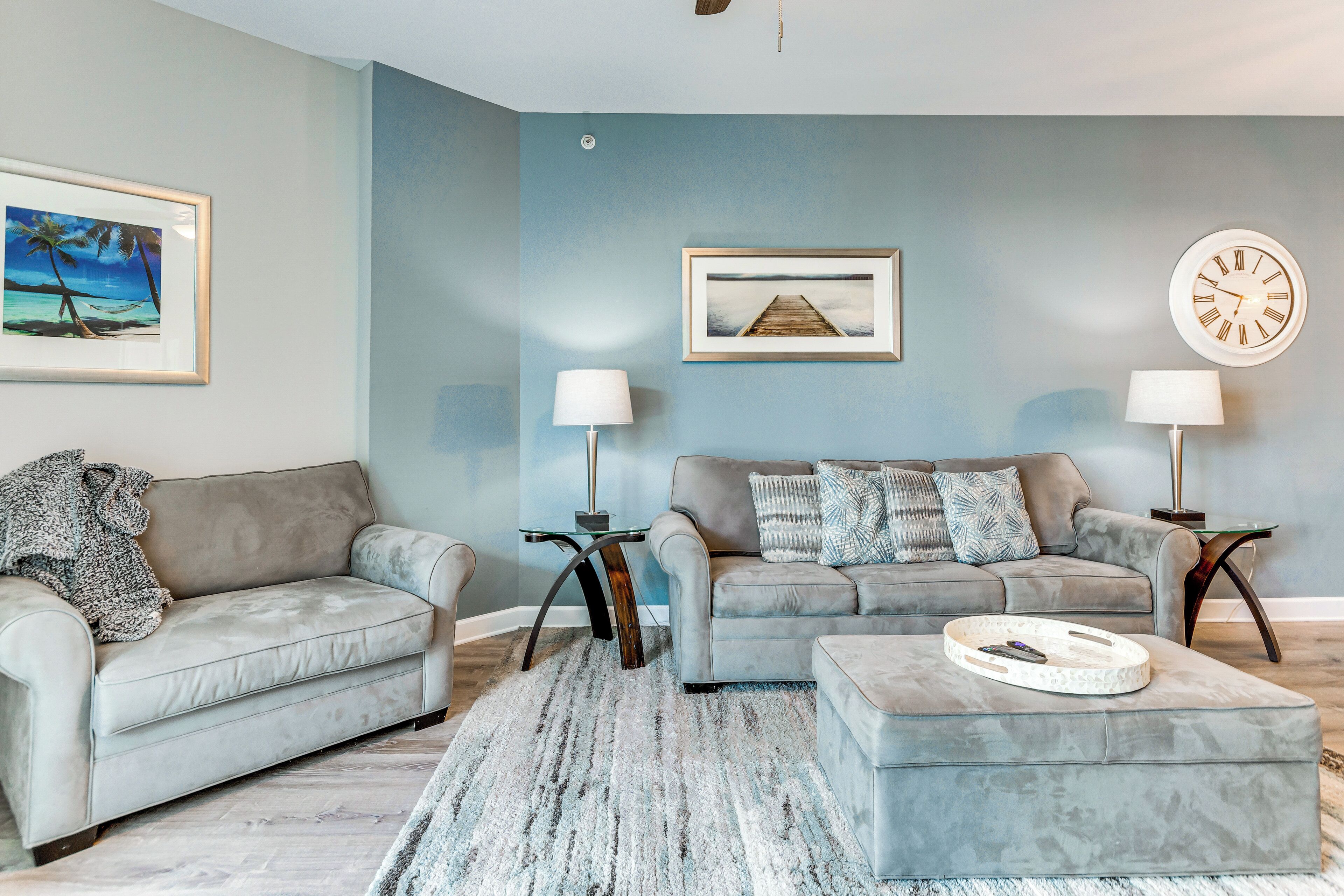 A living room with two grey sofas, a coffee table, a rug, and wall-mounted lamps.
