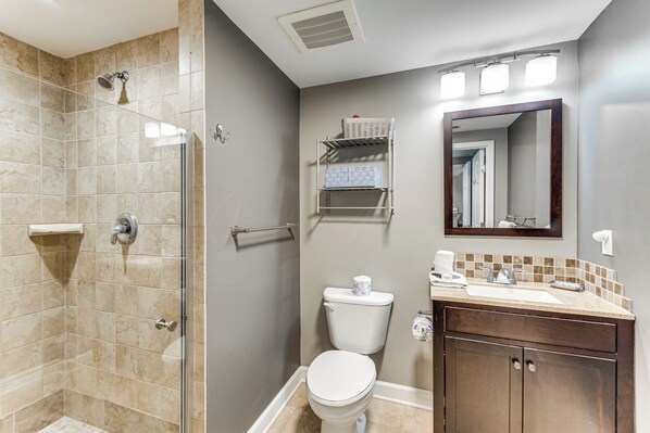 A bathroom with a shower, toilet, sink, and a mirror. - 1 Mi to Henderson Beach: Condo w/ Resort Perks! (Destin)