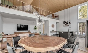 A spacious living area with a large round wooden table, a TV, and a balcony.