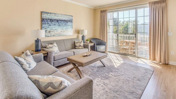 A living room with a sofa set, a coffee table, and a painting on the wall. - Beach Shuttle & Pool: North Myrtle Beach Condo! (North Myrtle Beach)