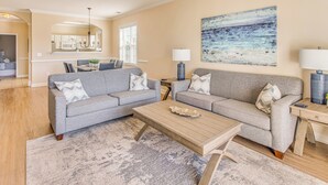A living room with a grey sofa set, a wooden coffee table, and a painting on the wall. - Beach Shuttle & Pool: North Myrtle Beach Condo! (North Myrtle Beach)