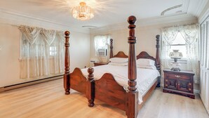 Uma cama de dossel com estrutura de madeira e um candelabro sobre ela.