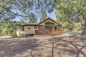 A two-story house with a stone facade, a wooden deck, and a chimney. - 1 Mi to Downtown Ruidoso: Peaceful Forested Cabin! (Ruidoso)