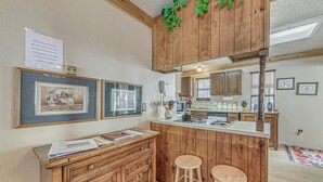 A kitchen with wooden cabinets, a bar area with stools, framed pictures on the wall, and a sign with temperature instructions.