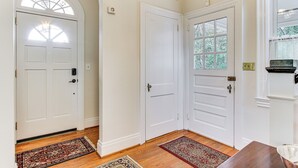 A hallway with white doors, a chandelier, and a window with a view of greenery. - 3 Mi to Augusta National: Historic Home w/ Patio (Augusta)