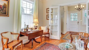 A dining area with a wooden table, chairs, a chandelier, and a view of the outdoors through a window. - 3 Mi to Augusta National: Historic Home w/ Patio (Augusta)