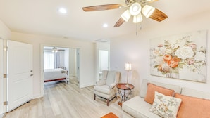 A spacious room with a ceiling fan, a bed, a sofa, and a painting on the wall. - Patio & Workspace: Peaceful Riverside Apartment! (Riverside)