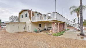 A two-story house with a covered porch, a brick foundation, and a white railing. - Patio & Workspace: Peaceful Riverside Apartment! (Riverside)