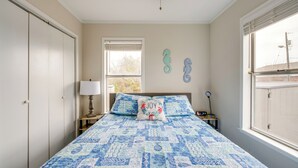 Een slaapkamer met een bed, een raam, een nachtkastje en een kledingkast.