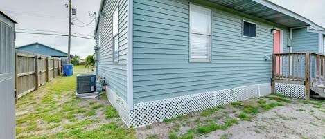 A single-story house with a front porch, a small attached garage, and a backyard with a lawn and a wooden fence.
