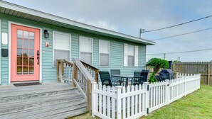 Een huis met een houten terras, een rode deur en een witte picket fence.