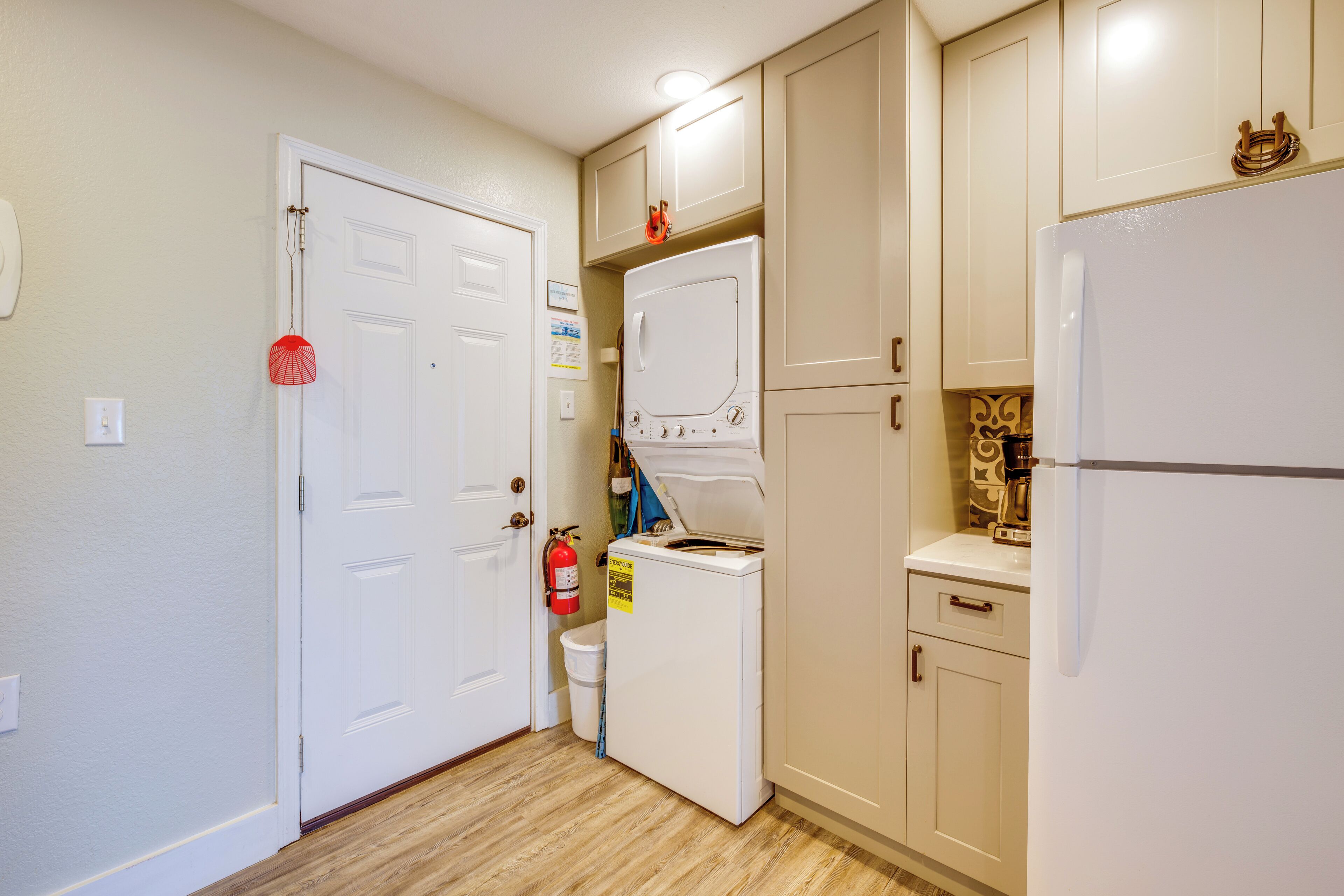 A compact kitchen with a white refrigerator, a washing machine, and a small countertop.