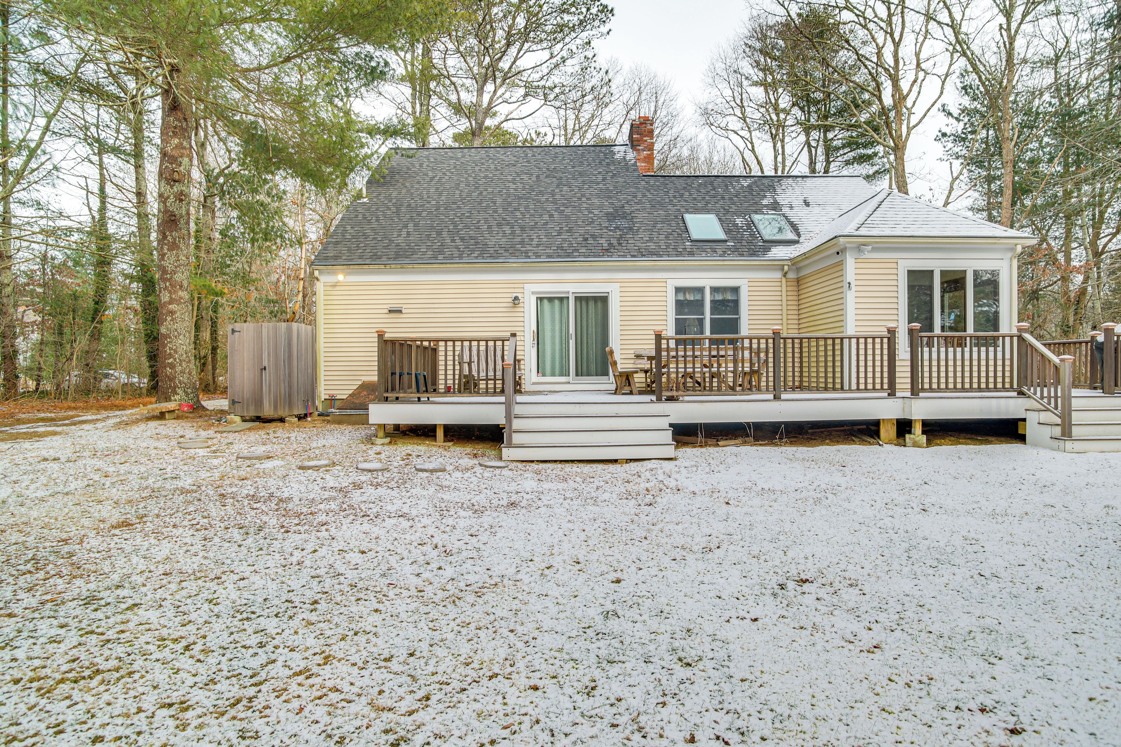 A single-story house with a deck, surrounded by trees.